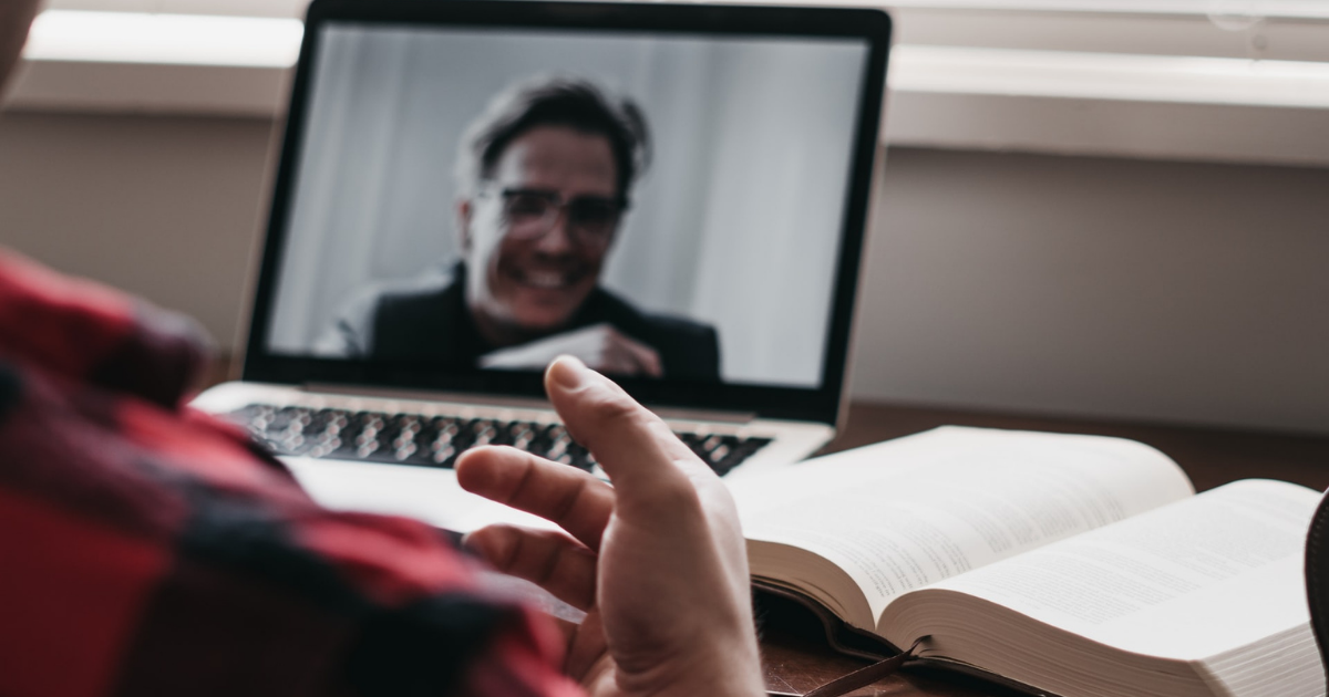 pessoa em frente a uma aula online com um caderno ao lado