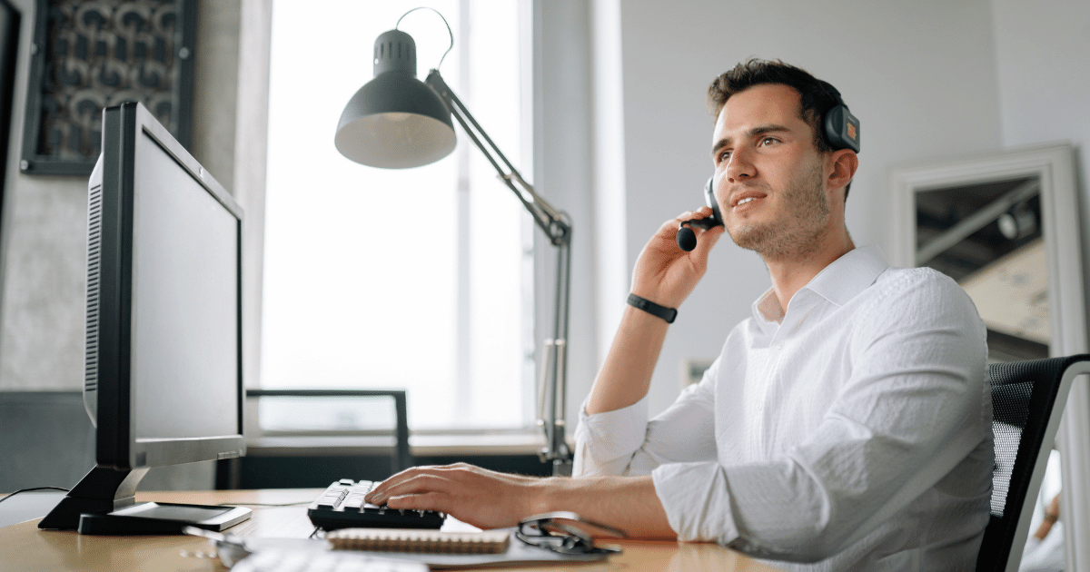 homem em frente ao computador atendendo telefone
